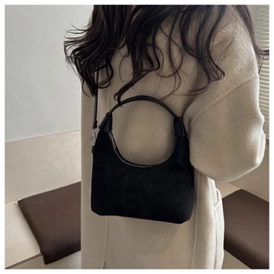 Détail du sac hobo en daim noir montrant la texture mate et la bandoulière portée