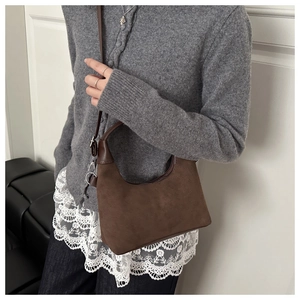 Détail du sac demi-lune en daim vintage avec texture café et fermeture argentée