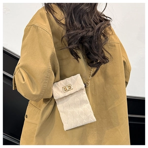 Detail of cream quilted plush handbag with a gold twist lock and fine metal chain strap