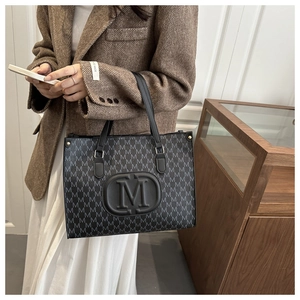 Macro shot of dark grey tote bag with letter print pattern and round 3D logo detail