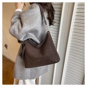 Detail of dark brown tote bag showing contrast stitching and hanging coin purse