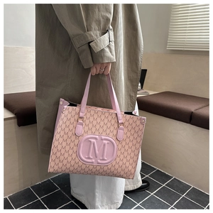 Detail of pink tote bag with M letter prints and 3D embossed logo held by model