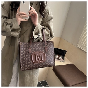 Detail of vintage tote bag featuring brown canvas with M-letter monogram print