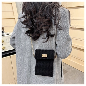 Detail of a black quilted crossbody bag with a gold chain and metal twist lock