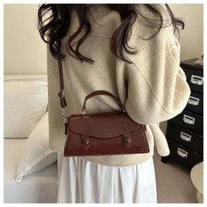 Deep red crossbody bag detail showing leather texture and adjustable shoulder strap