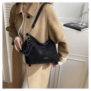 Detail of black matte leather shoulder bag with white contrast stitching and mini pouch