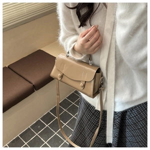 Detail of a khaki vintage faux leather handbag held by a model in casual attire