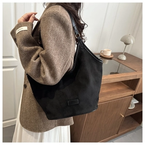 Detail of minimalist black matte tote bag with slim shoulder strap and golden buckle