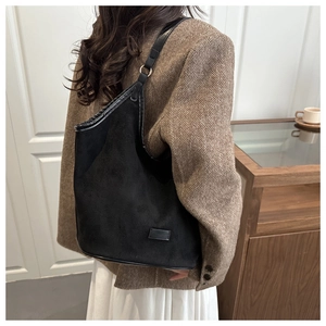 Detail of minimalist black faux suede tote bag featuring sleek curved top and rectangular patch