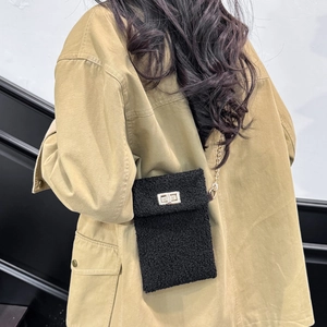 Faux fur black crossbody phone bag with gold chain strap shown on model side profile