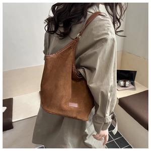 Close-up of brown suede tote bag featuring premium leather trim and shoulder strap details