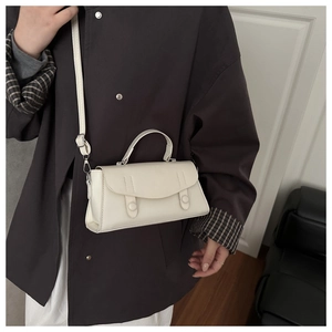Close-up of a white rectangular handbag featuring double snap buttons and top handle