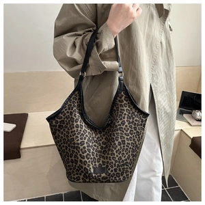 Detailed view of large leopard print tote bag with black straps on a model in a minimal setting