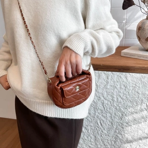 Brown quilted mini moon bag with gold floral clasp and chain strap in a lifestyle setting