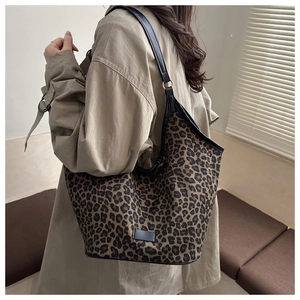 Detail of large leopard print tote bag with black leather straps and trim on a model