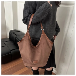 Detail of large brown suede hobo bag with smooth leather trim and minimalist leather patch