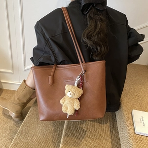 Brown faux leather tote bag with long straps and cute plush bear charm for daily commute