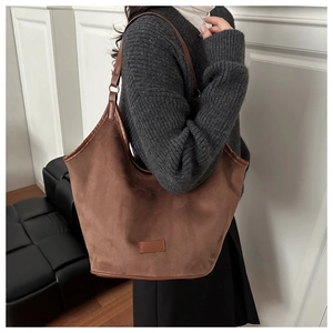 Brown suede hobo tote bag detail with adjustable strap on a model for winter fashion