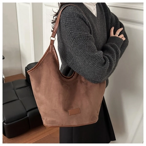 Close-up of brown suede tote bag with leather piping and adjustable metal ring buckle