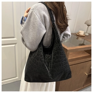 Detail of a large leopard print tote bag worn on shoulder in a cozy indoor setting