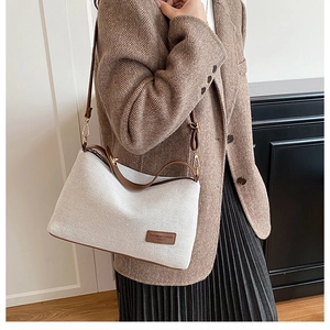 Detail of canvas crossbody bag with brown leather trim and fashion brand patch
