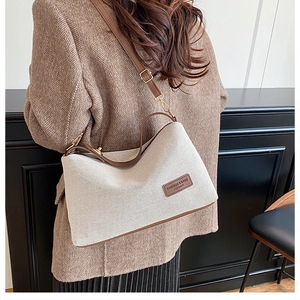 Modella che indossa una borsa a tracolla in tela beige con finiture in pelle marrone