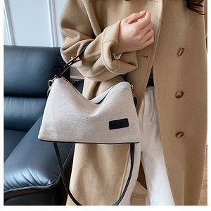 Dettaglio borsa hobo in maglia bianco panna con tracolla in pelle nera e logo