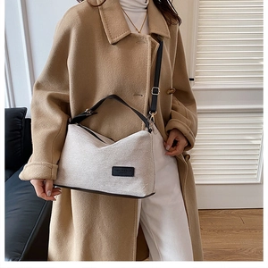 Dettaglio borsa a spalla in tela con patch logo in pelle nera e spalline a contrasto