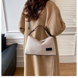 Dettaglio della borsa a mezzaluna in tela beige con finiture in pelle nera e targhetta