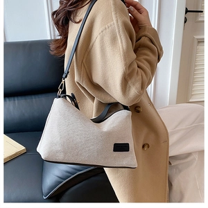 Dettaglio della borsa a tracolla in tela beige con finiture in pelle nera e logo