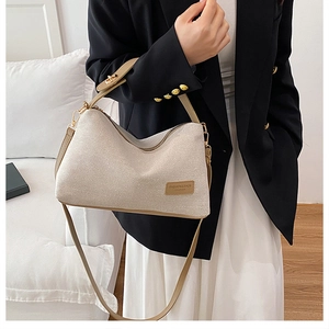 Dettaglio della borsa tote in tela beige con cinturini in pelle marrone e zip metallica