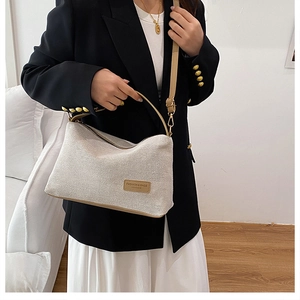 Dettaglio della borsa a tracolla intrecciata beige con cinturino in pelle e finiture dorate