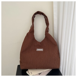 Detail of brown corduroy tote bag featuring striped texture and a FASHION woven label