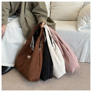 Detail showing pleated fabric texture and fashion labels on four large corduroy tote bags