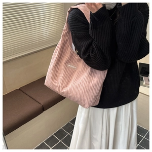 Pink pleated tote bag detail showing fashion woven label and wrinkled fabric texture