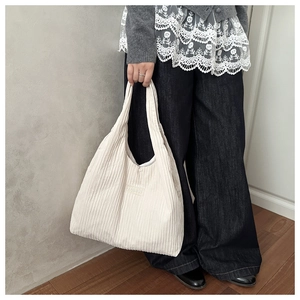 Close-up of beige corduroy tote bag featuring vertical stripes and a fashion label
