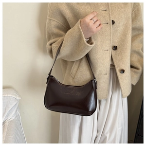 Detail of a dark brown leather underarm bag featuring a minimalist embossed logo