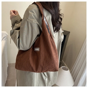 Detail of dark brown pleated tote bag with FASHION label and wide shoulder strap