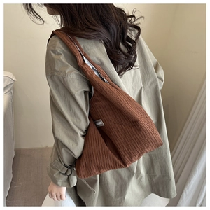 Detail of a dark brown pleated shoulder bag showing the vertical texture and fashion label