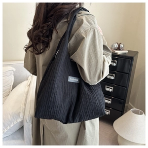 Detailed view of the black pleated canvas tote bag with fashion label in a home setting