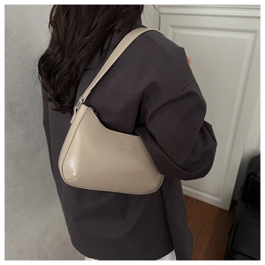 Detailaanzicht van een beige minimalistische schoudertas gedragen met grijs shirt