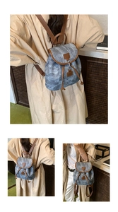 Dettaglio dello zaino in tela blu con spalline in pelle marrone e chiusura a coulisse