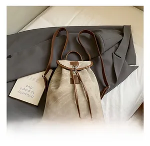 Detail of beige suede backpack showing drawstring closure and brown leather trim accents