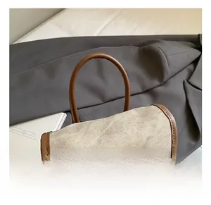 Detail of the gray canvas backpack featuring brown leather handles and premium stitching