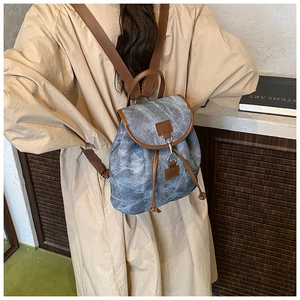 Vue arrière d'un sac à dos en toile bleu marine et cuir marron porté par un modèle