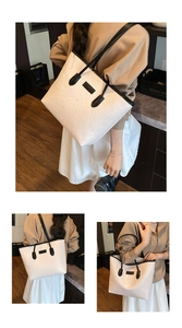 Detail of white embossed monogram tote bag with black handles in cozy interior setting