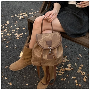 Detail of vintage brown canvas backpack featuring premium leather trim and metal buckle closure