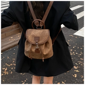 Detailed back view of a retro brown canvas backpack on a model in an urban street setting