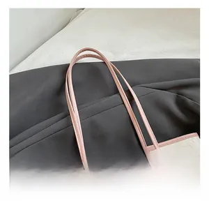 Detail of pink faux leather handles and embossed pattern on a beige tote bag