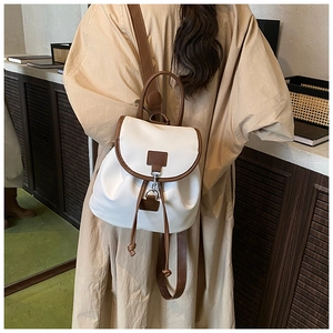 Detail of minimalist white and brown contrast backpack worn on a beige shirt